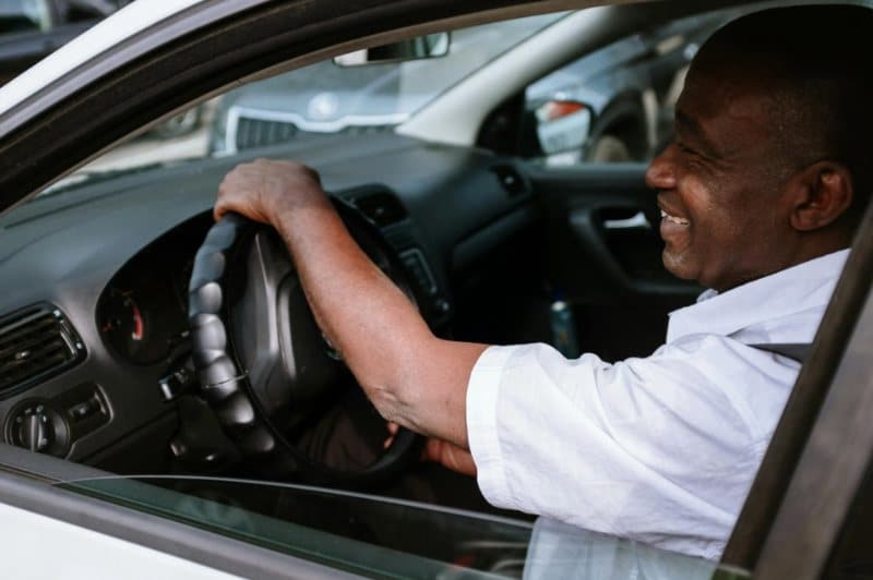 A man driving and smiling in his car, relaxed and confident.