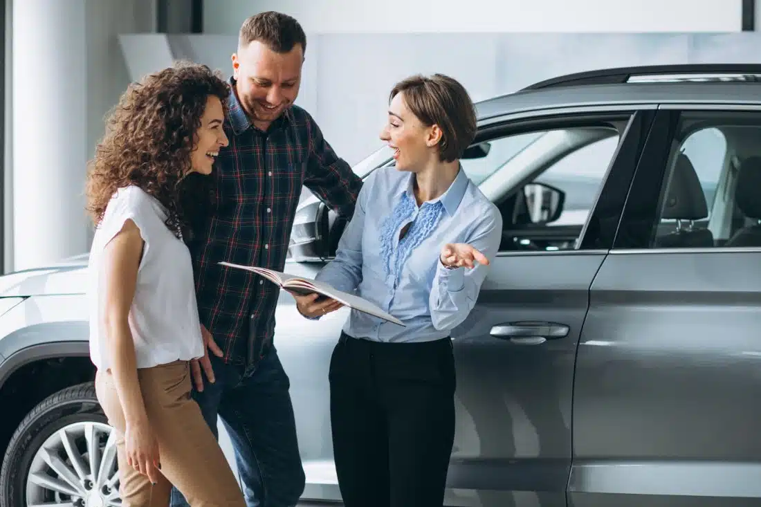 A couple discusses vehicle financing options with a sales representative inside a dealership, exploring quick cash solutions like title pawns in Clay County.